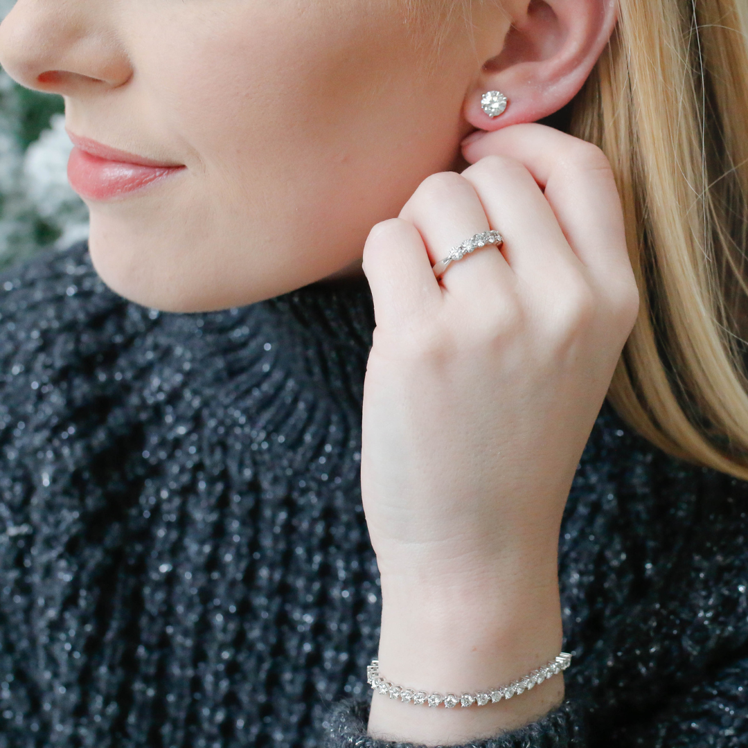 Woman wearing Hearts on Fire diamond stud earrings, diamond bracelet and ring