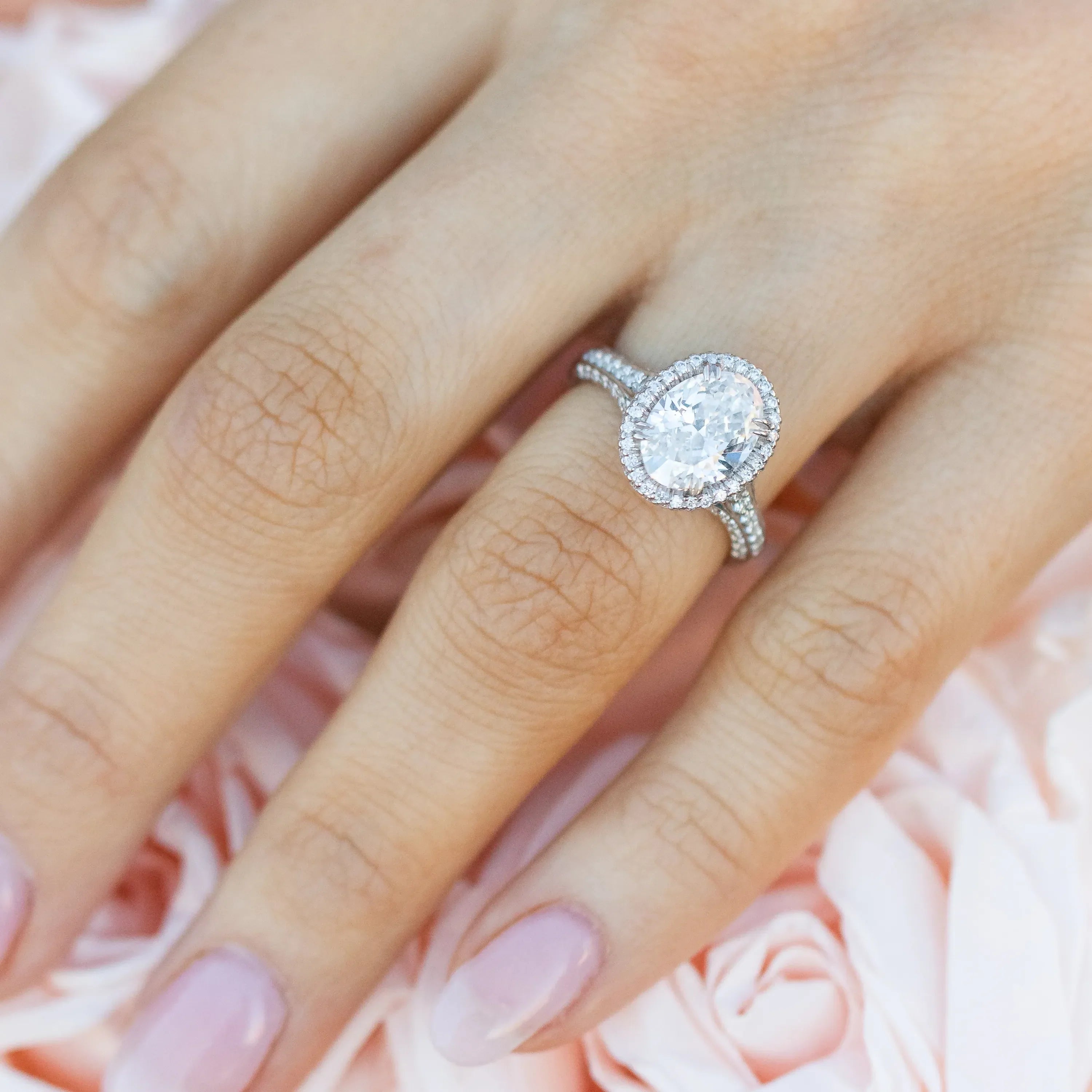 Close-up of a woman’s hand wearing an elegant oval engagement ring